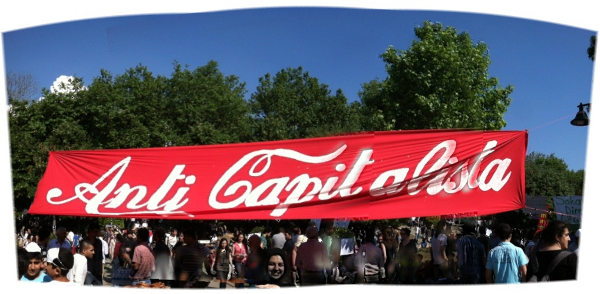 (image of protesters flying “anti-capitalista” banner